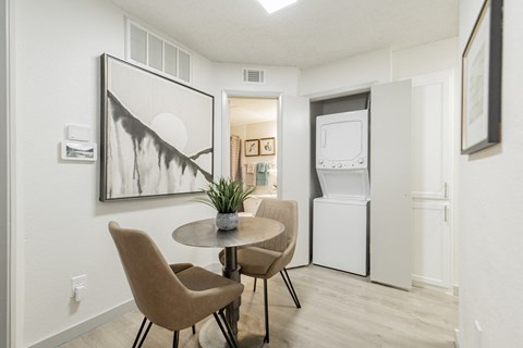 A dining room with a table and chairs and a framed artwork on the wall.
