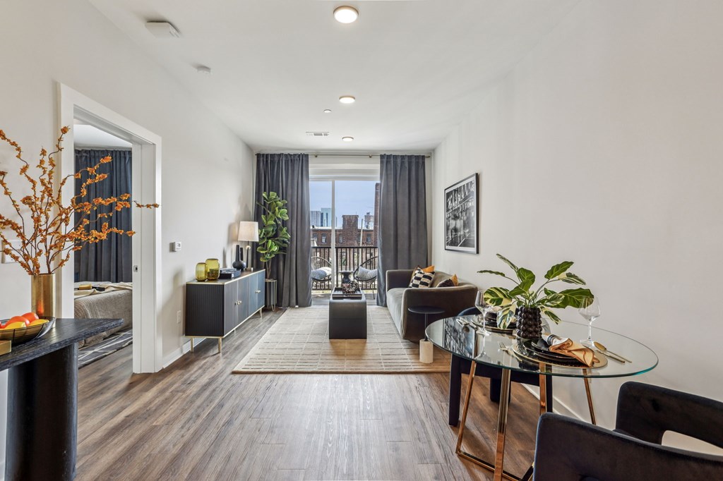 A modern living room with a glass table and black chairs.