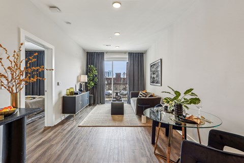 A modern living room with a glass table and black chairs.