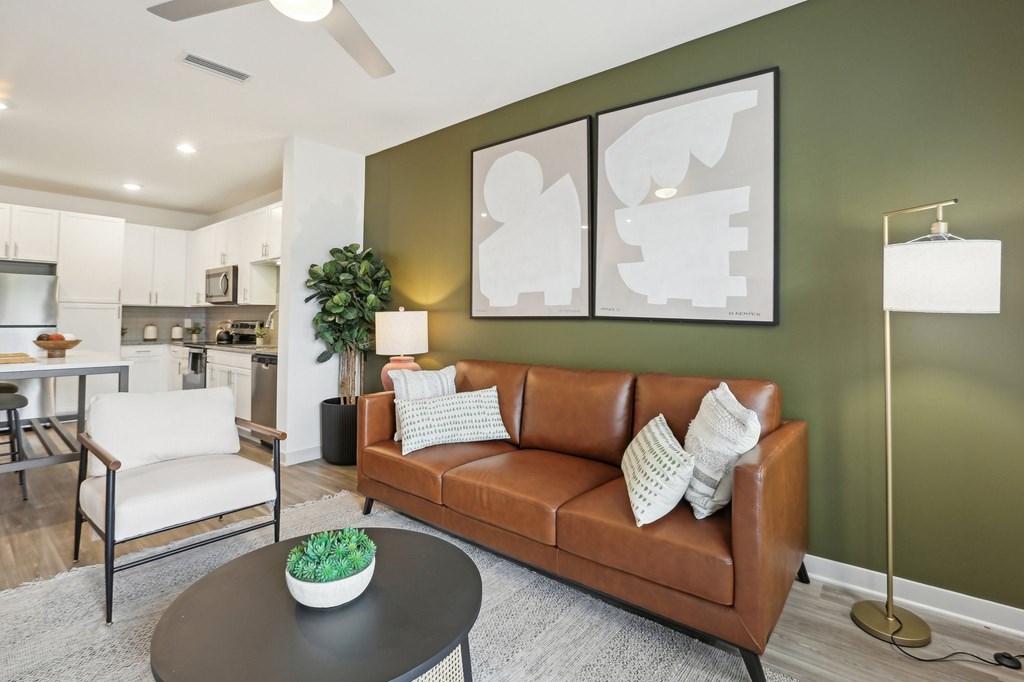 A living room with a brown couch, a black coffee table, and a green plant.