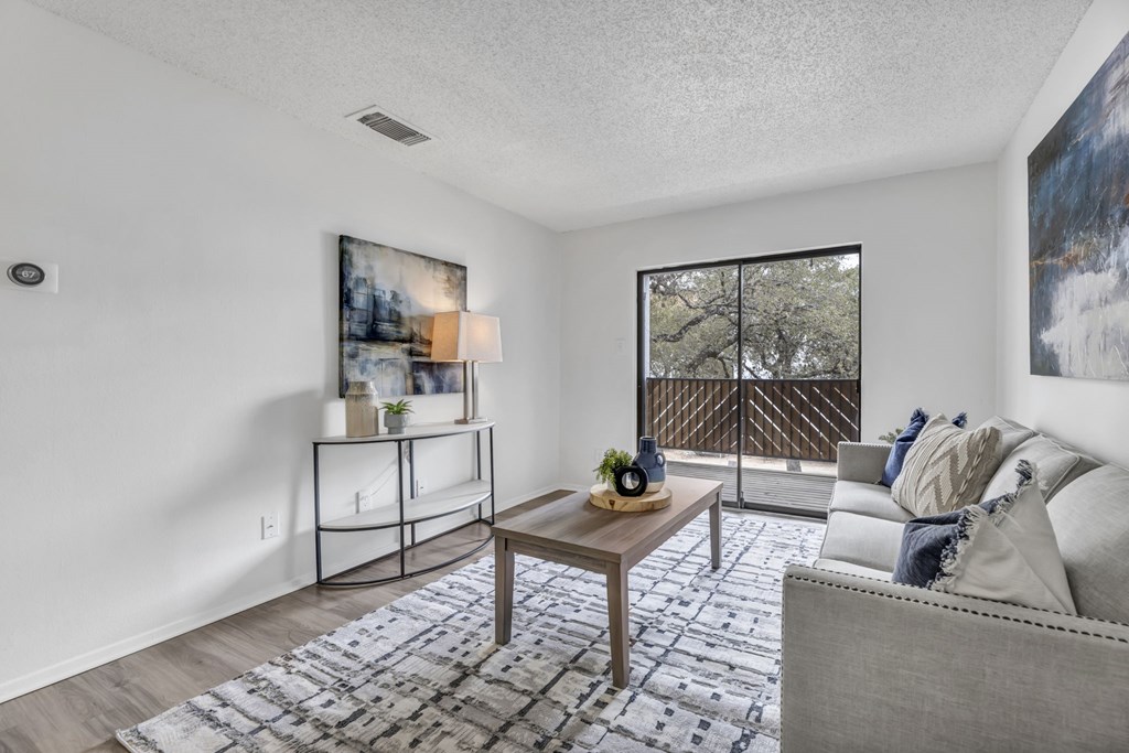 A living room with a grey couch, a wooden coffee table, and a painting on the wall.