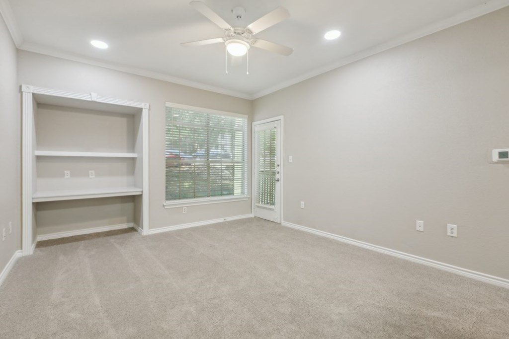 A room with a ceiling fan and a window with blinds.