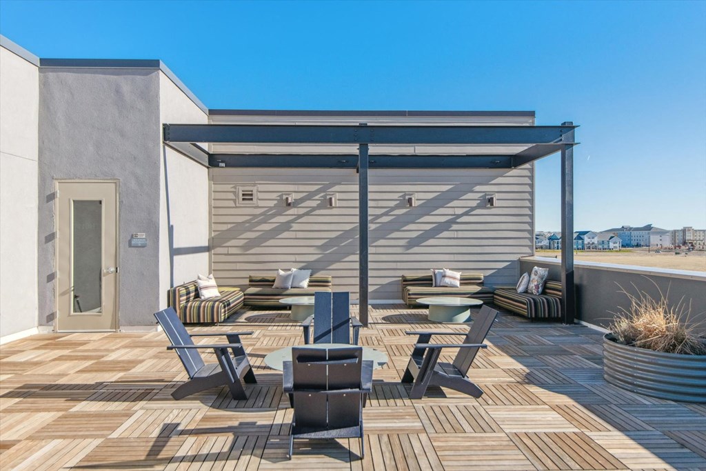 A patio with a table and chairs is set up on a wooden deck.