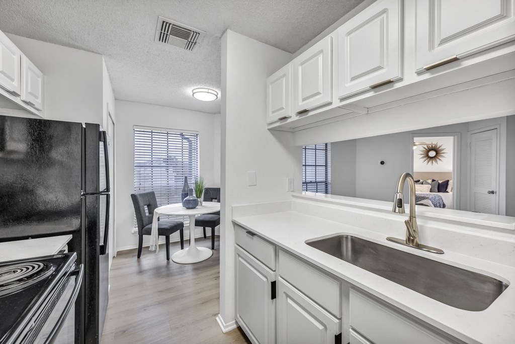 A kitchen with white cabinets and a black refrigerator.