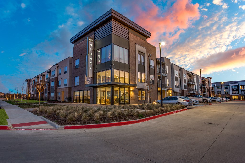 an apartment building at dusk with the sun setting behind it