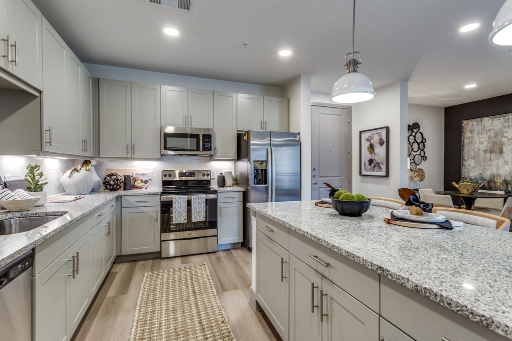 an open kitchen with white cabinets and granite counter tops