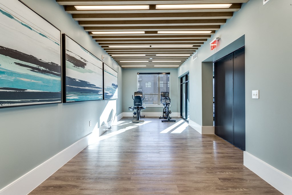 a hallway with a chair and paintings on the wall and a door