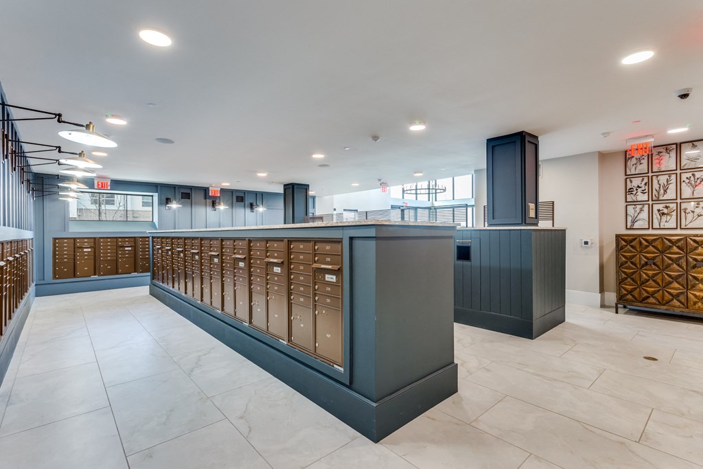 a large lobby with a counter with mailboxes and a staircase