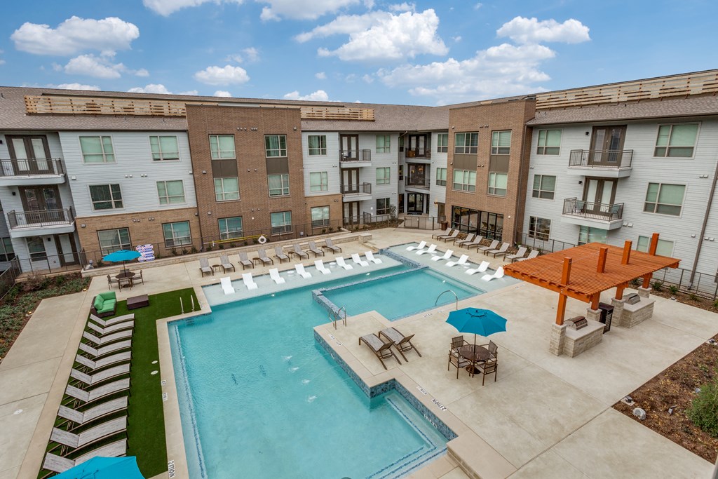 a resort style pool with lounge chairs and umbrellas in front of a building