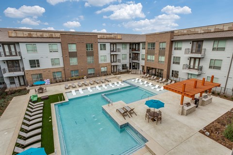 a resort style pool with lounge chairs and umbrellas in front of a building