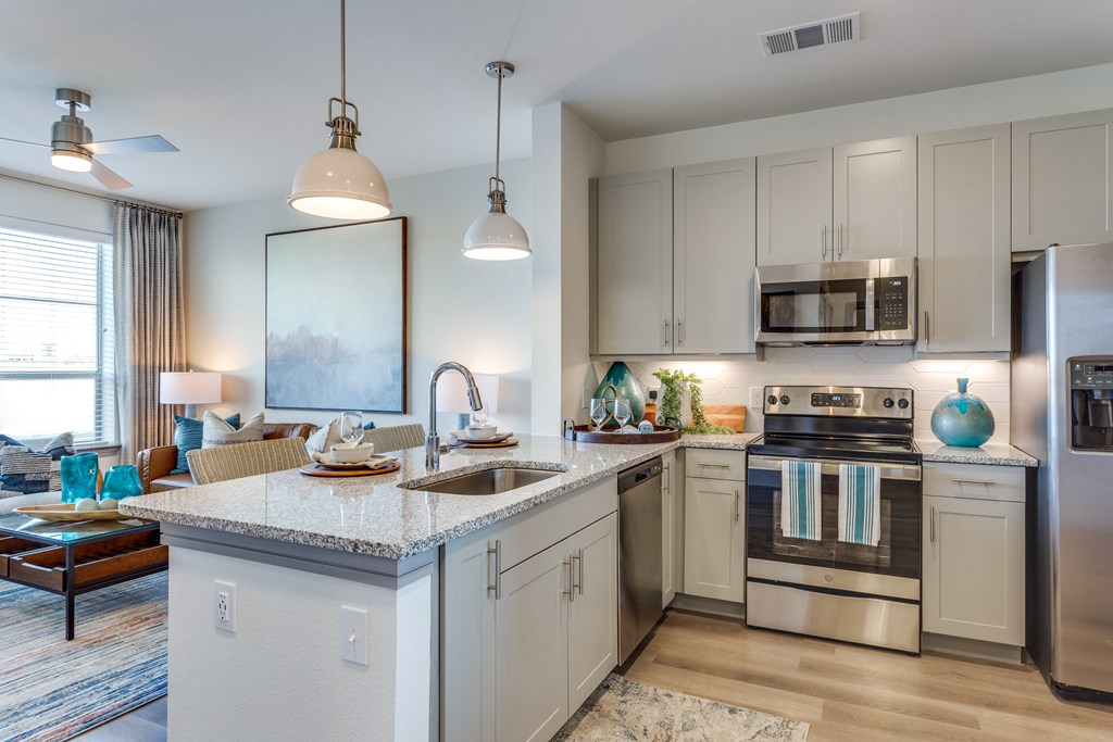an open kitchen and living room with an island and stainless steel appliances