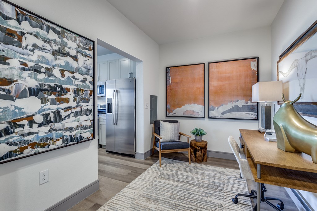 views of a kitchen and living room with a desk and chair and a refrigerator