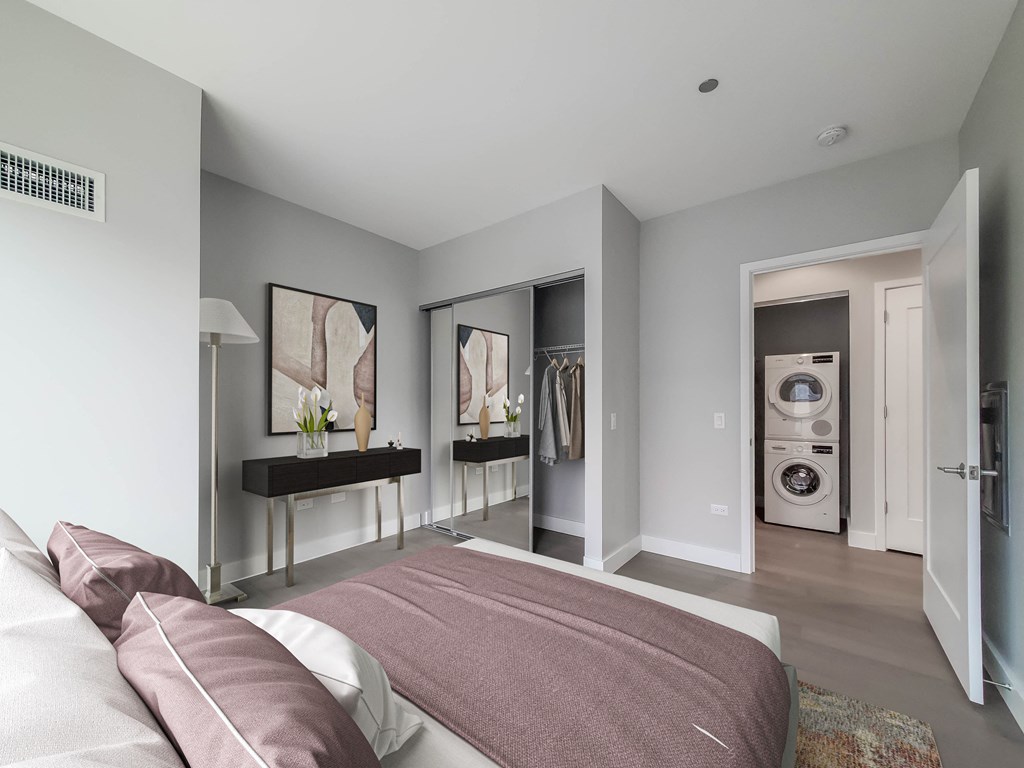A bedroom with a bed and a washing machine in the laundry area.
