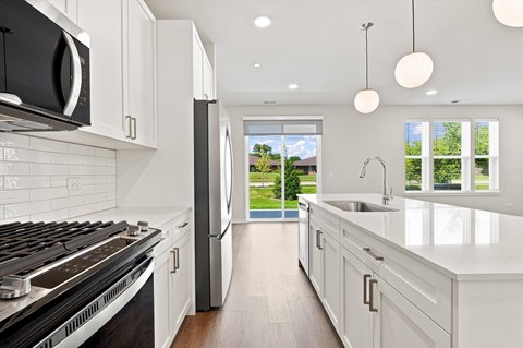 A modern kitchen with white cabinets and a black stove top.