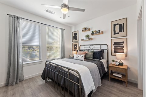 A bedroom with a large bed and a ceiling fan.