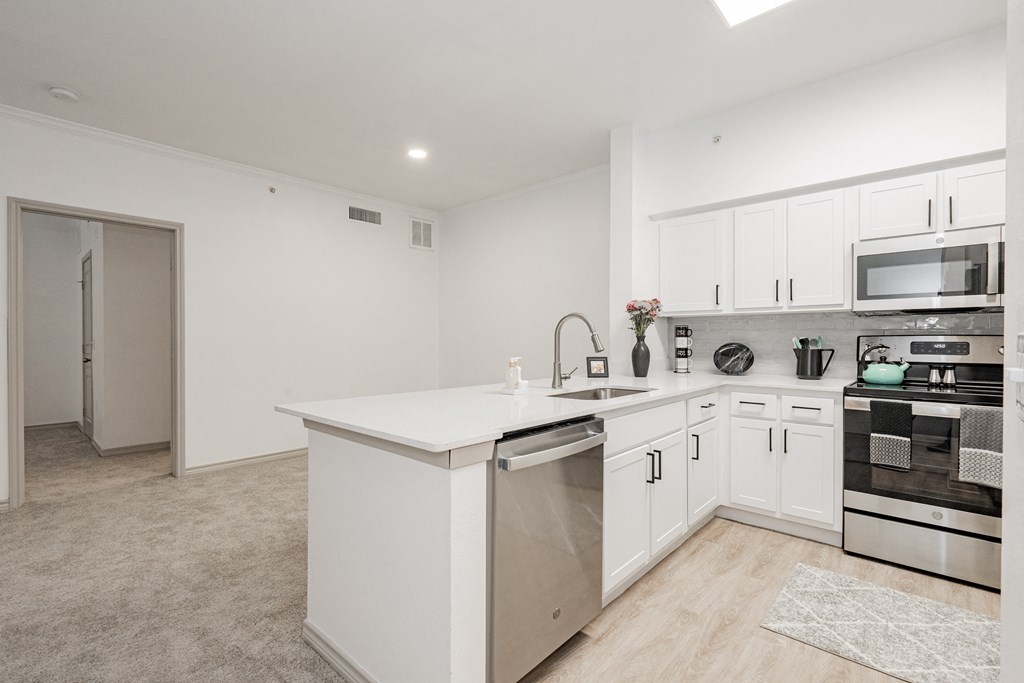 a white kitchen with an island and stainless steel appliances