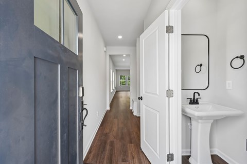 A long hallway with a sink and mirror at the end.