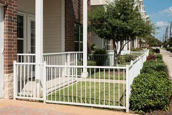 A white fence surrounds a brick house.