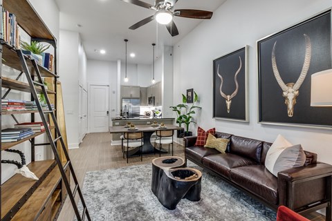 A living room with a brown leather couch and a wooden bookshelf.