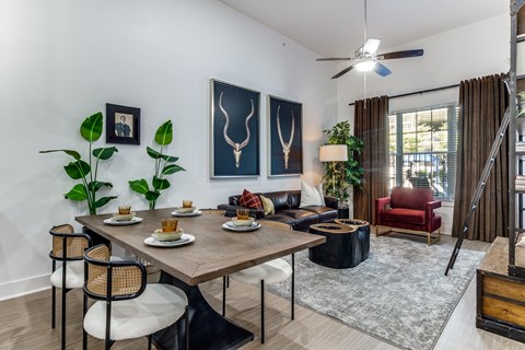 A dining room with a table set for two and a red chair.