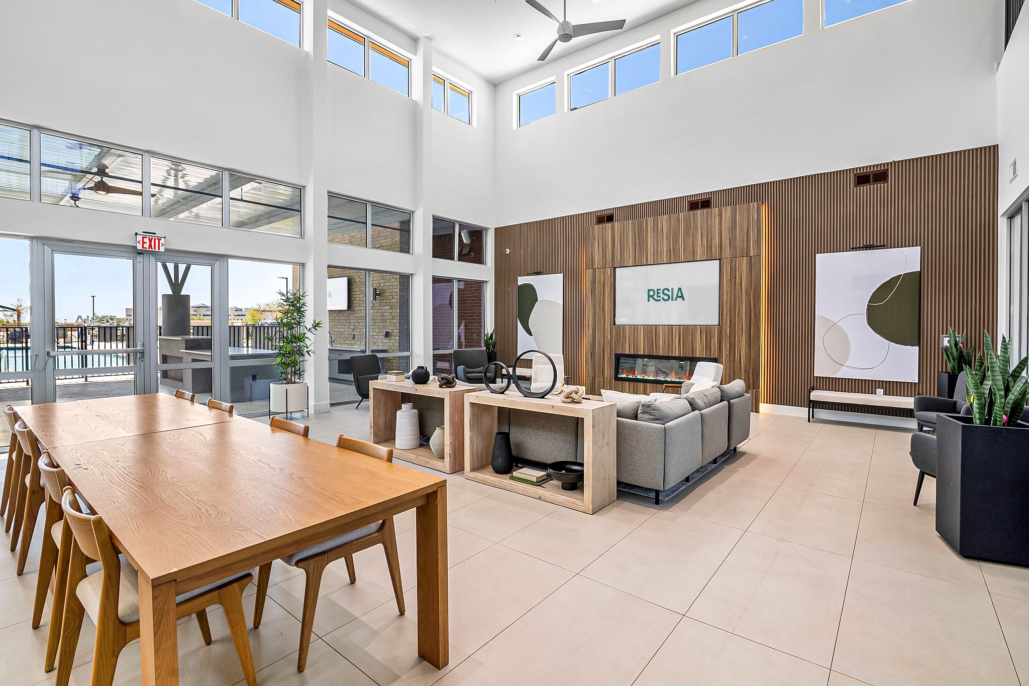 A modern office space with a long wooden table and chairs, a couch, and a reception desk with a sign that reads "RESIA".