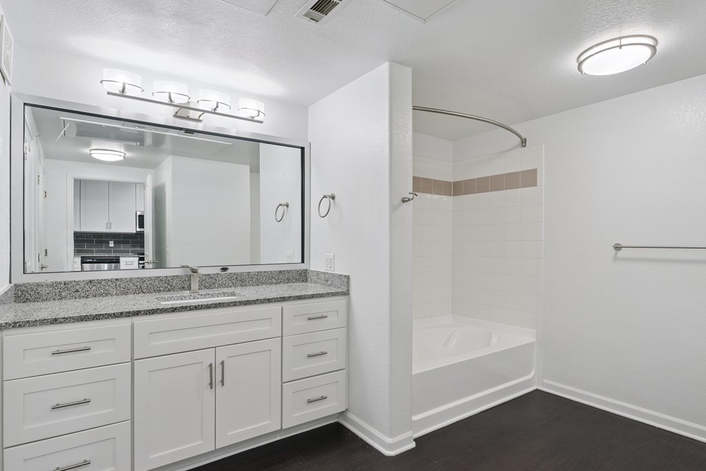 A white bathroom with a sink, mirror, and shower.