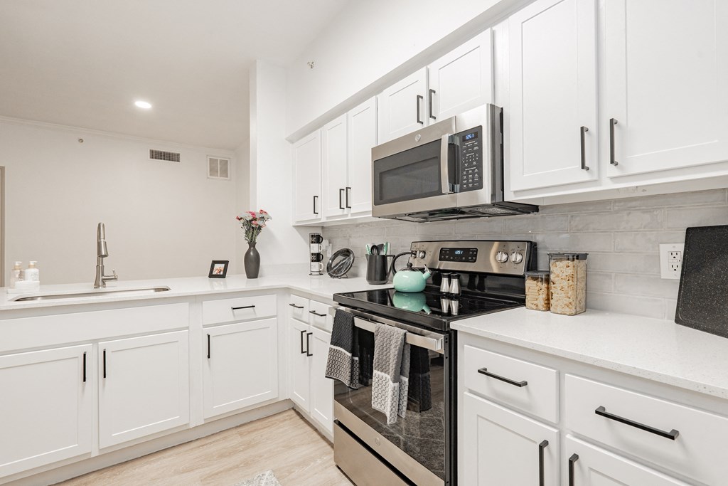 a kitchen with white cabinets and a stove and a microwave