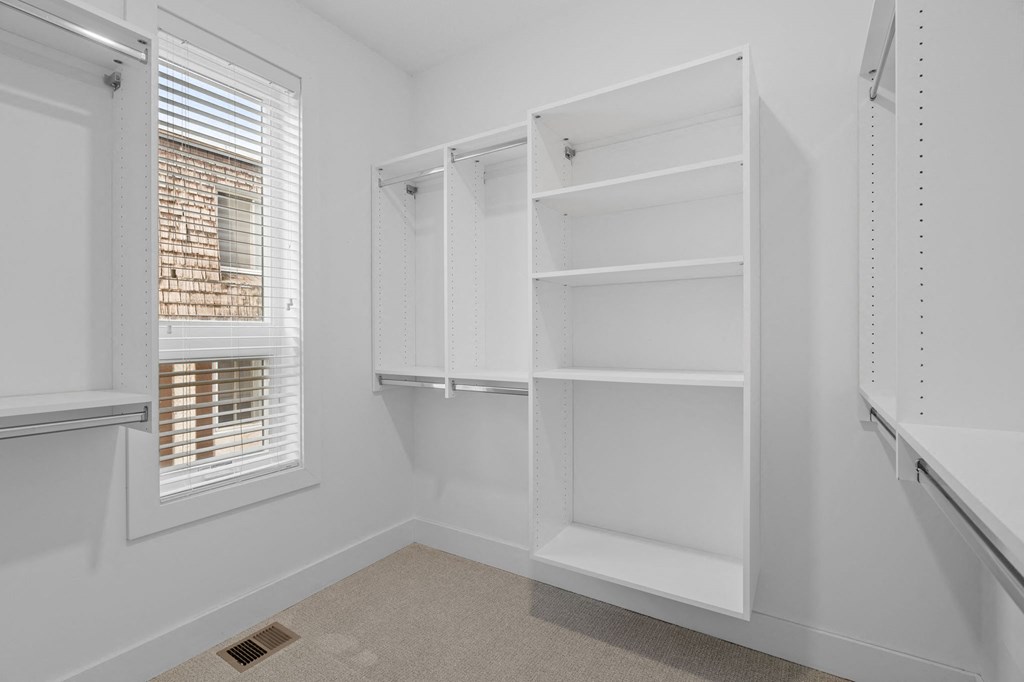 a white closet with white shelves and a window