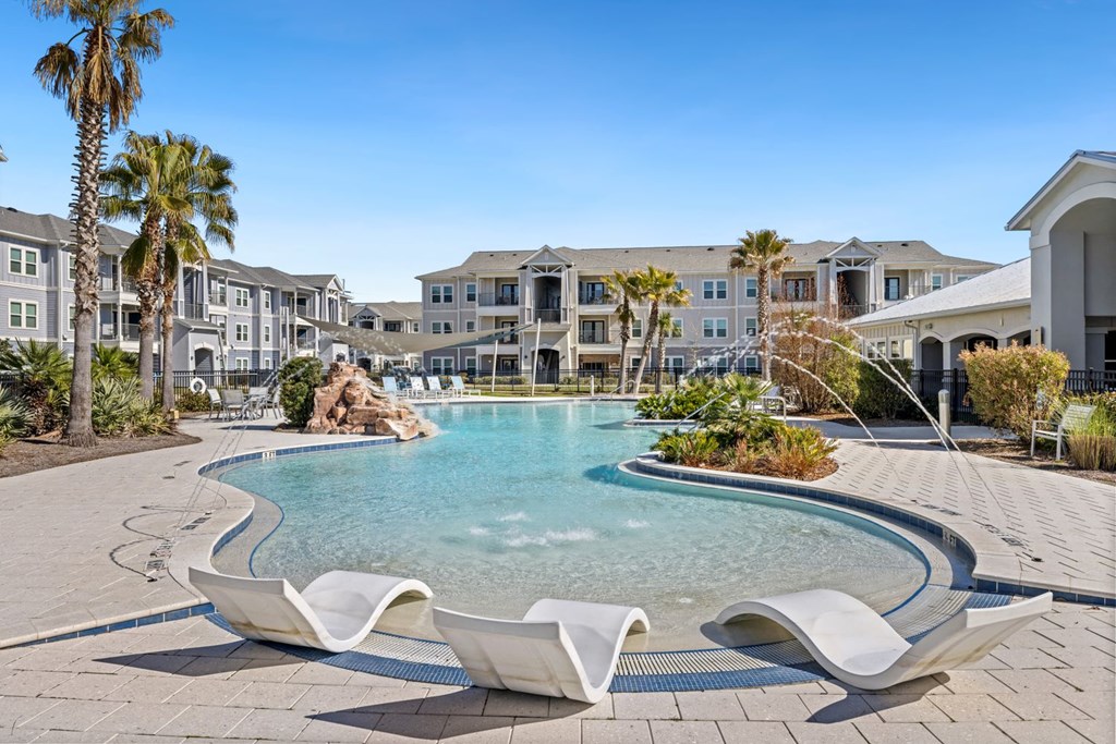 A pool surrounded by white lounge chairs and palm trees.