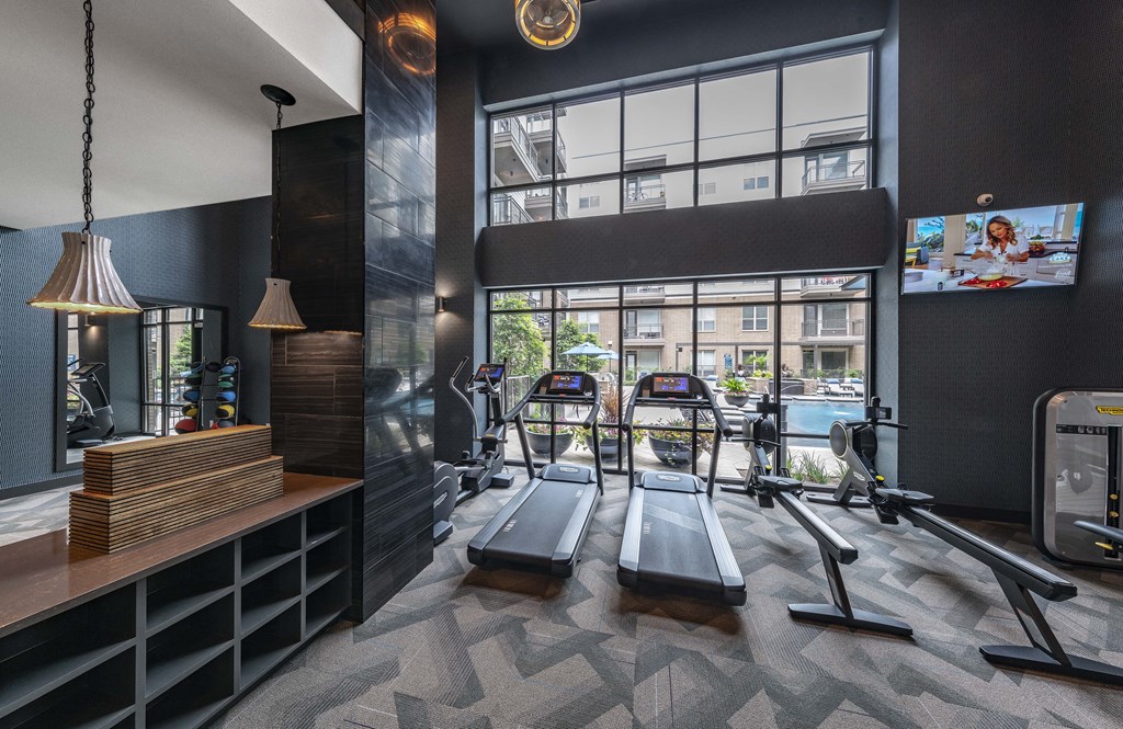 a gym with cardio equipment and a large window