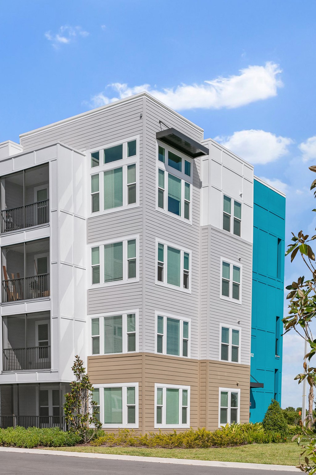 A modern multi-story building with balconies and a mix of white and brown exterior walls.