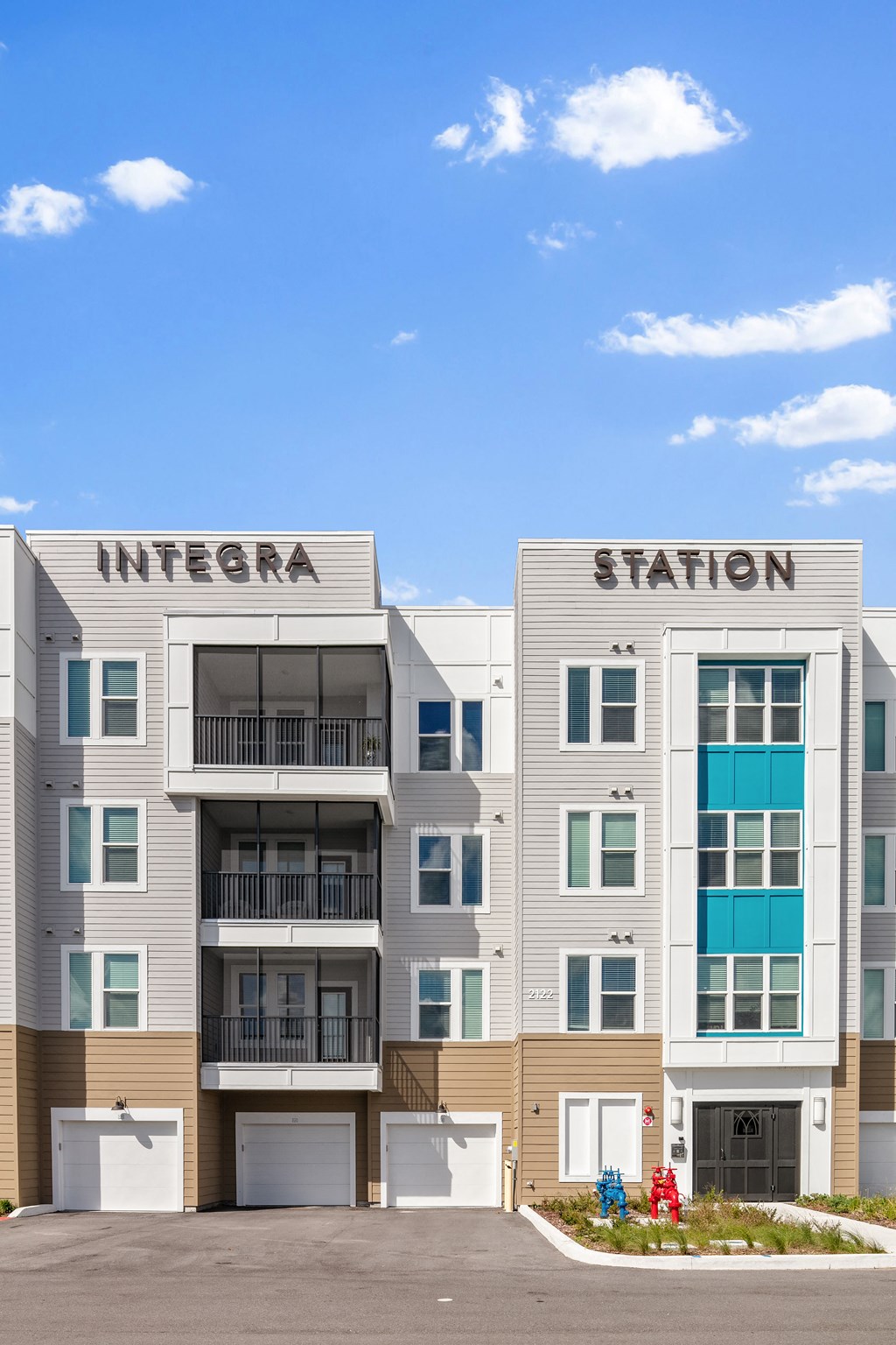 A modern apartment building named Integra Station with balconies and garage doors.