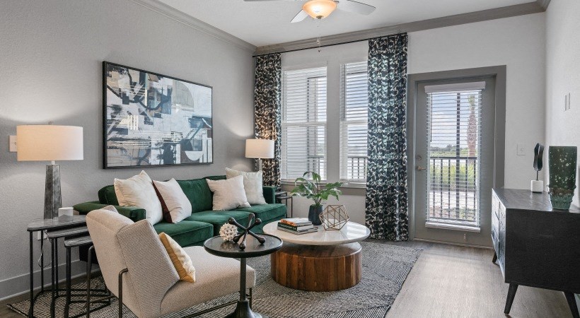 A living room with a green couch, a coffee table, and a painting on the wall.