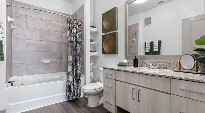 A modern bathroom with a white tub, toilet, and sink.
