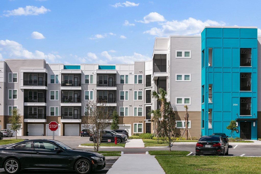 A black car is parked in front of a building with a stop sign.