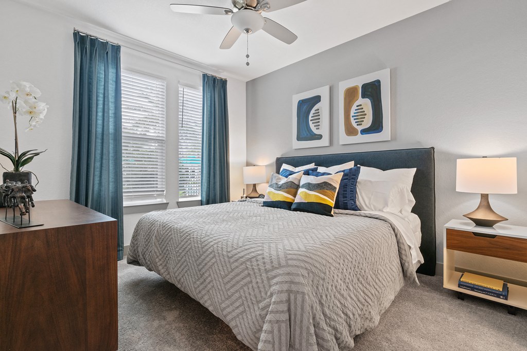 A bedroom with a bed, nightstand, and a ceiling fan.