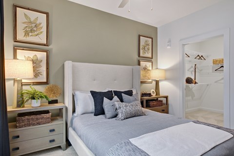 A bedroom with a large bed and a nightstand with a lamp.