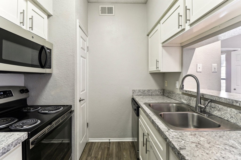 A kitchen with a stove, microwave, and sink.