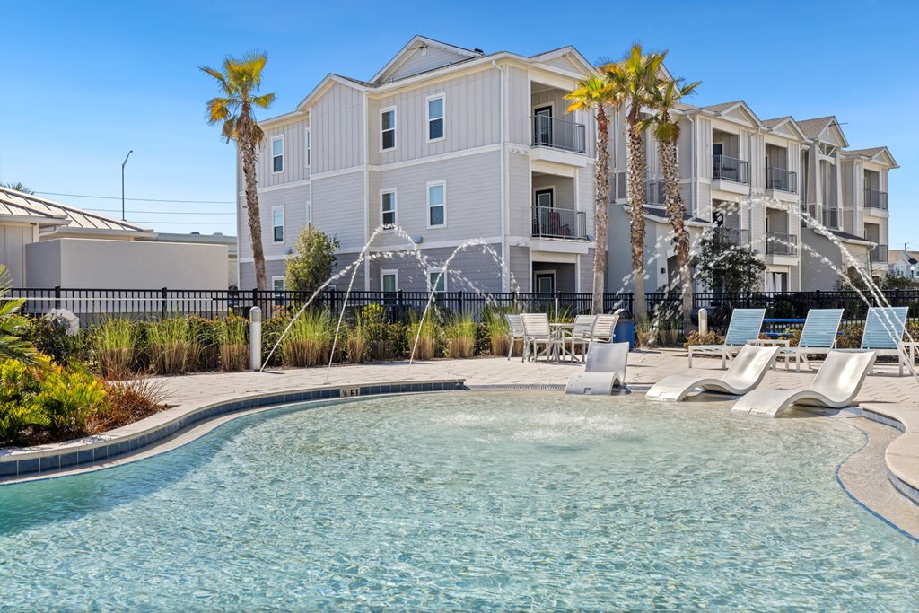 A pool in front of a building with palm trees.