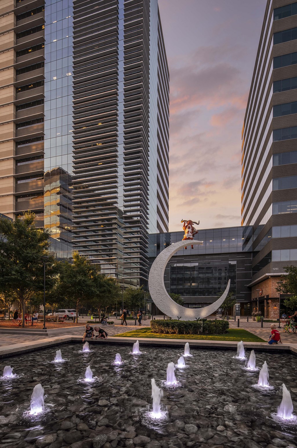 a skateboarder performs a trick on a water feature in front of two skyscrapers