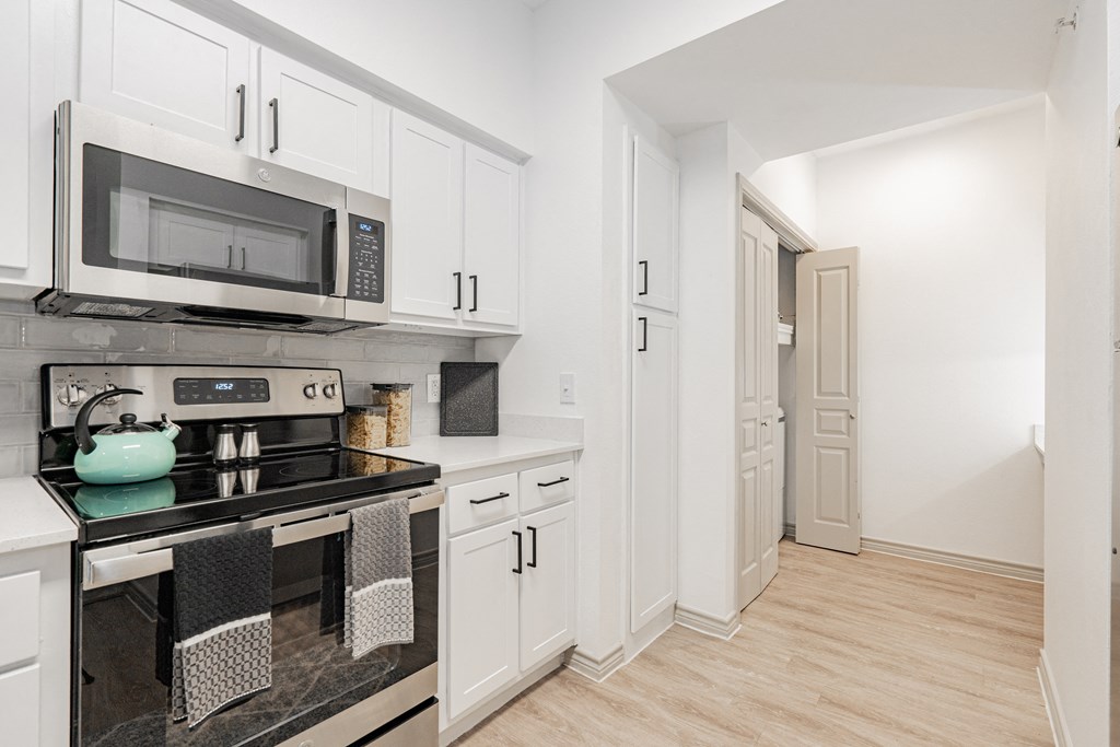 a kitchen with white cabinets and a stove and a microwave