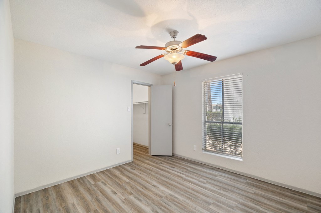 an empty living room with a ceiling fan and a window