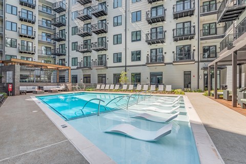 A large swimming pool in front of apartment buildings.