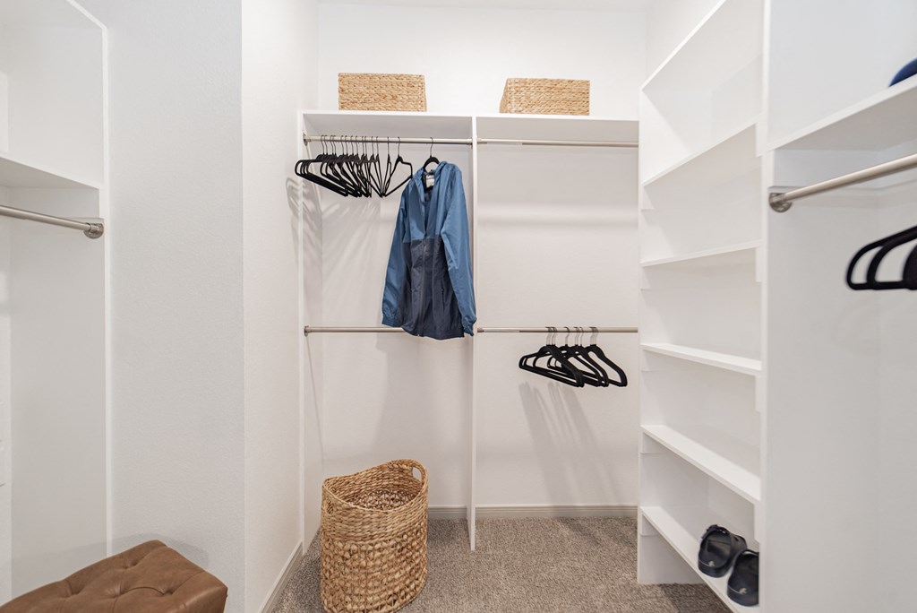 a walk in closet with white shelves and a closet organizer