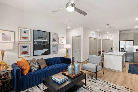 A living room with a blue couch and a ceiling fan.