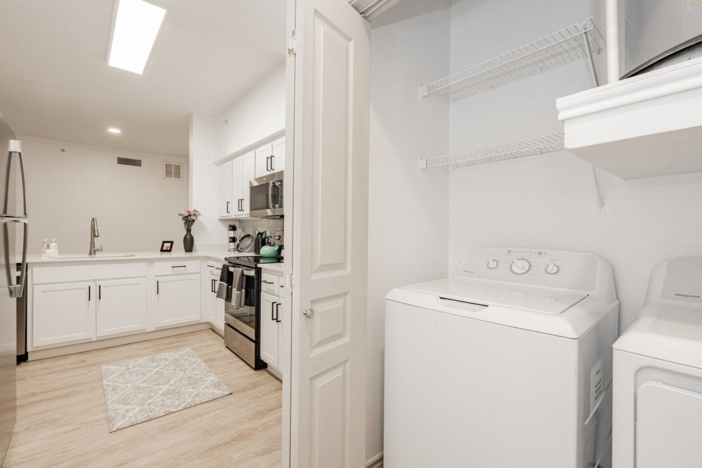 a laundry room with a washer and dryer and a kitchen with white appliances