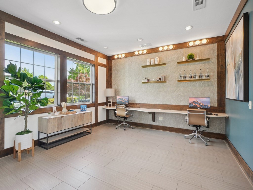 A room with a desk, chairs, and a potted plant.