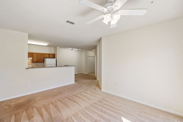 an empty living room and kitchen with a ceiling fan