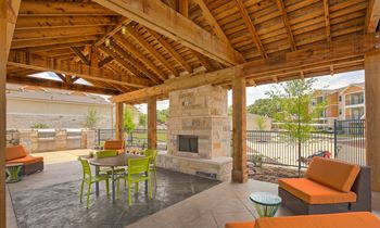 A patio with a fireplace and chairs.