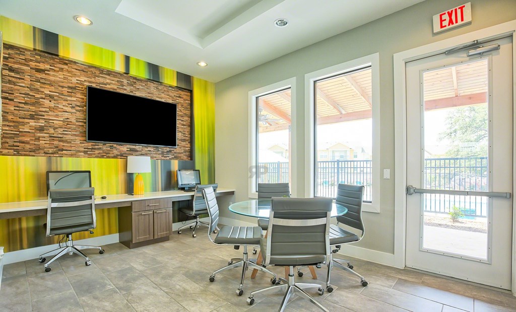 A conference room with a brick wall and a TV above the desk.